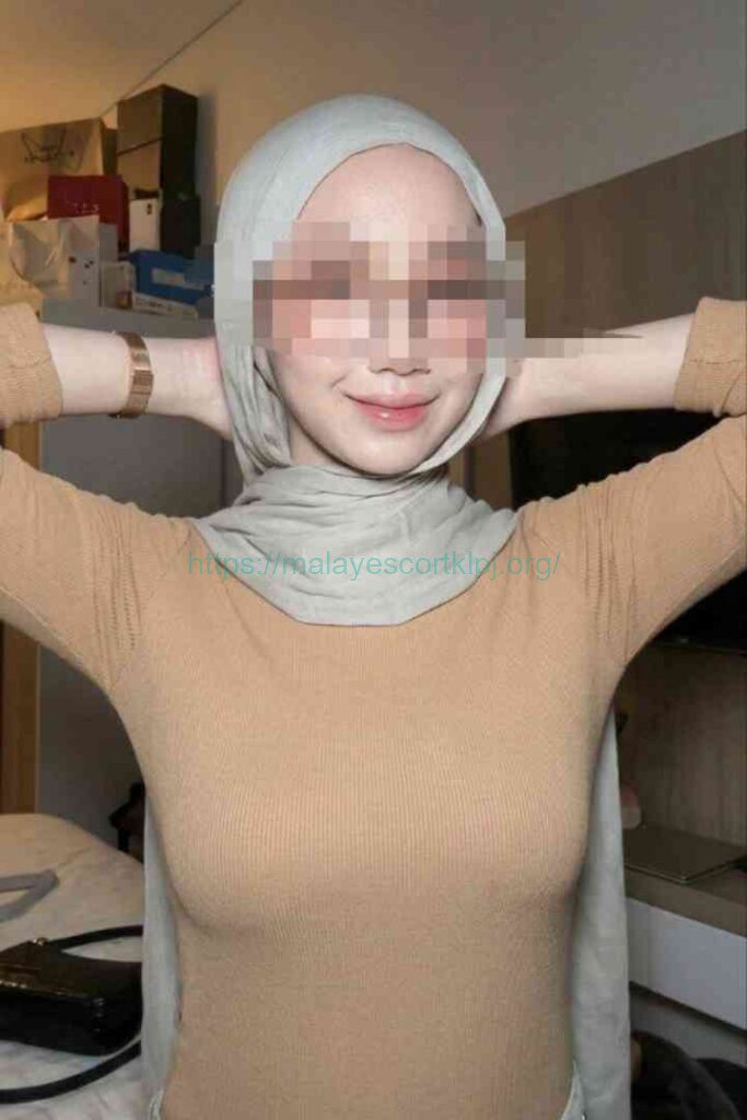 Woman in a beige top and hijab, arms behind her head